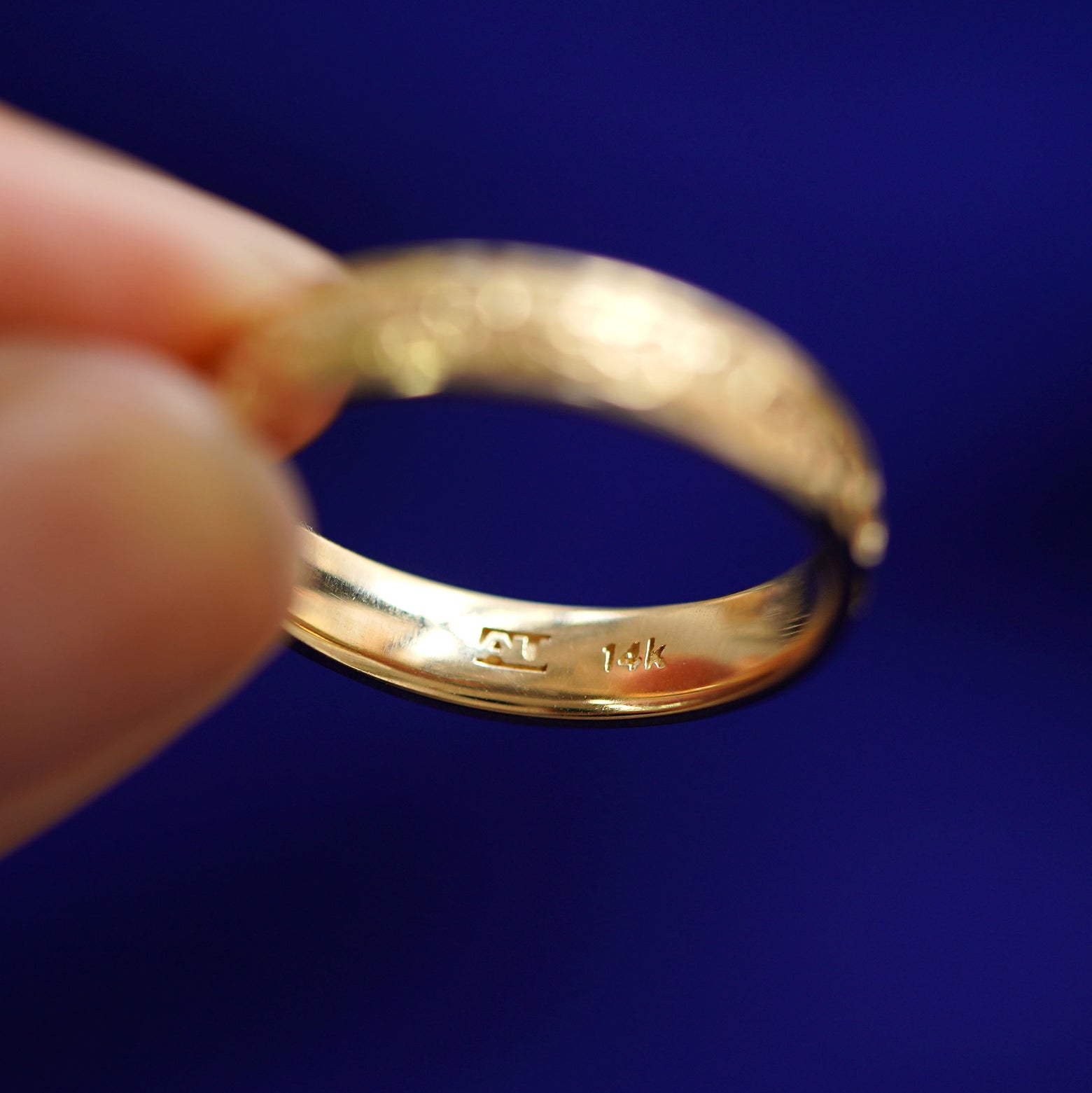 A model holding a 14k gold Filigree Band facing down between their fingertips to show the inside of the band