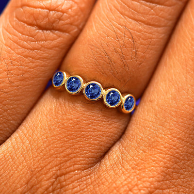 Close up view of a model's hand wearing a yellow gold 5 Gemstones Ring in sapphire