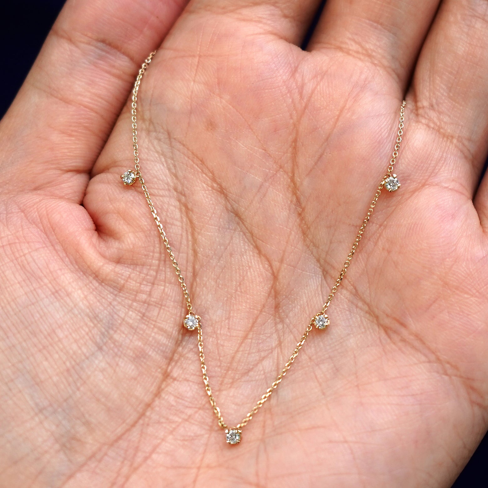 A yellow gold 5 Diamond Cable Necklace draped on a model's palm