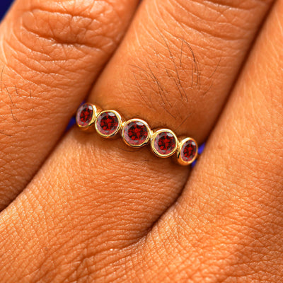 Close up view of a model's hand wearing a yellow gold 5 Gemstones Ring in garnet