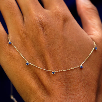 A solid gold sapphire 5 Gemstone Cable Necklace resting on the back of a model's hand