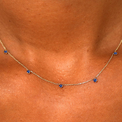 Close up view of a model's neck wearing a solid 14k yellow gold 5 Gemstone Cable Necklace in sapphire