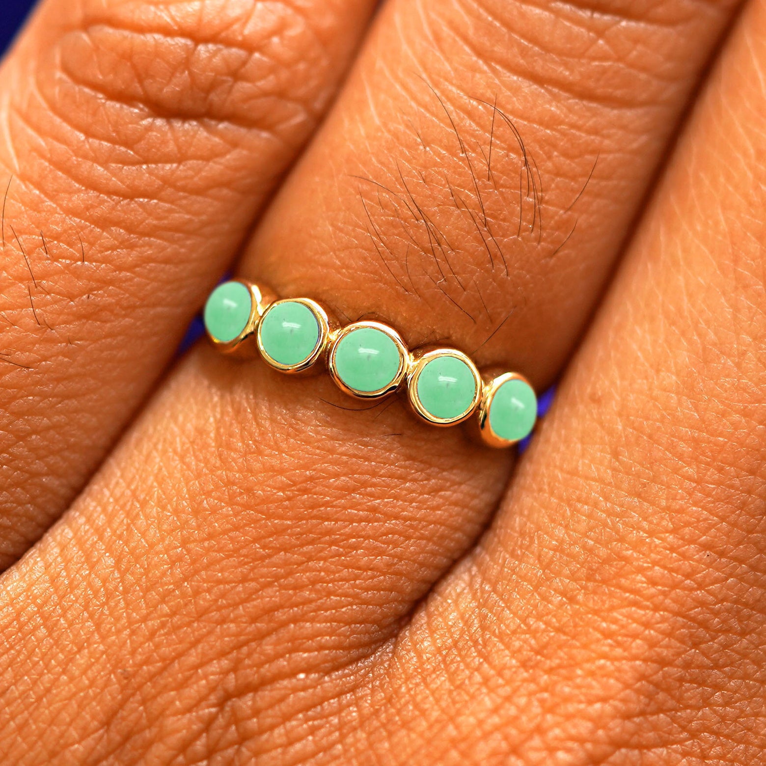 Close up view of a model's hand wearing a yellow gold 5 Gemstones Ring in jade