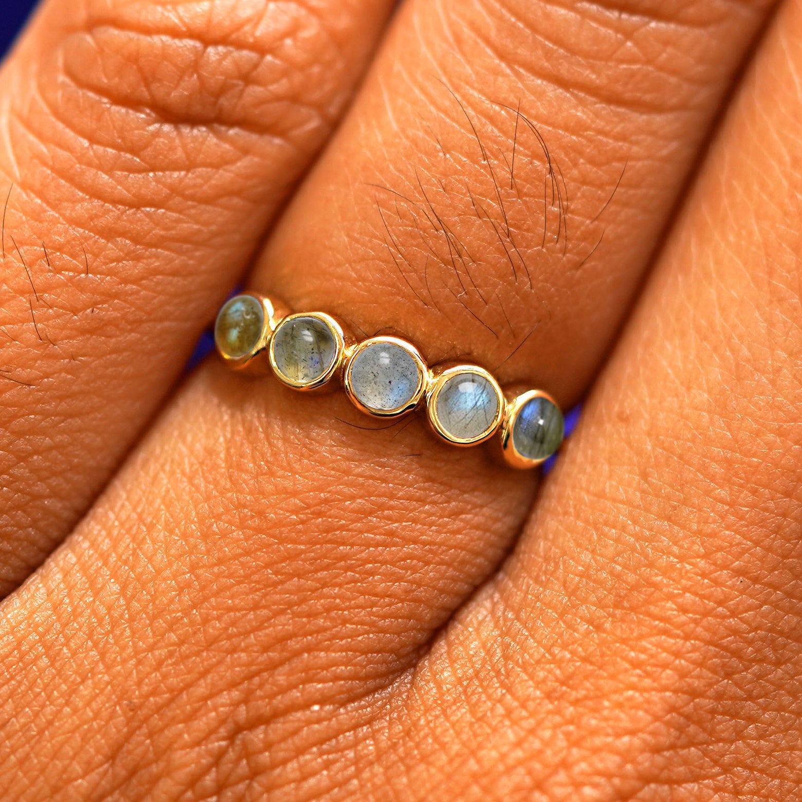 Close up view of a model's hand wearing a yellow gold 5 Gemstones Ring in labradorite