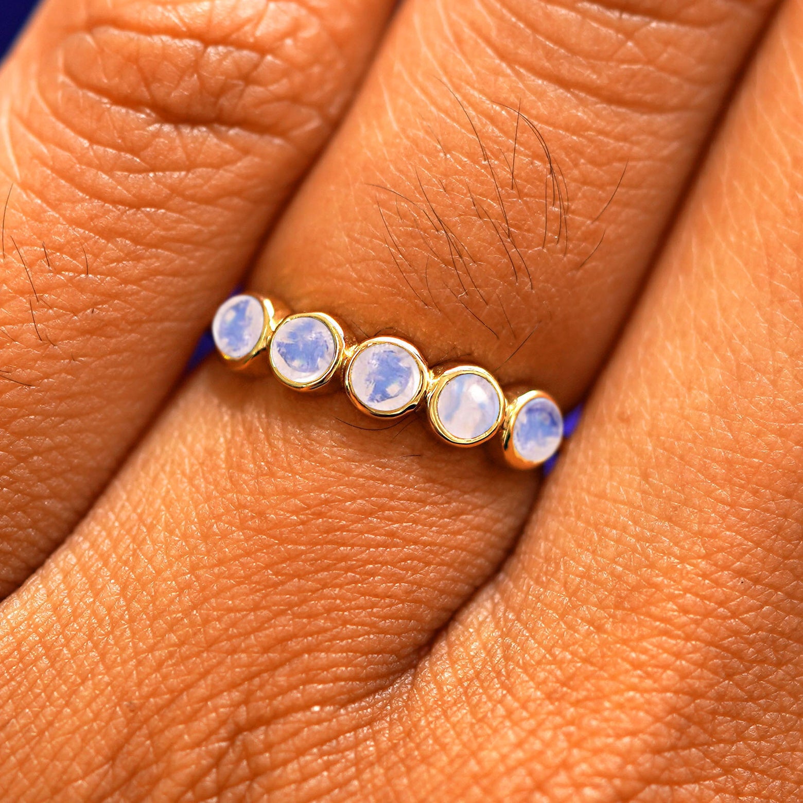 Close up view of a model's hand wearing a yellow gold 5 Gemstones Ring in moonstone