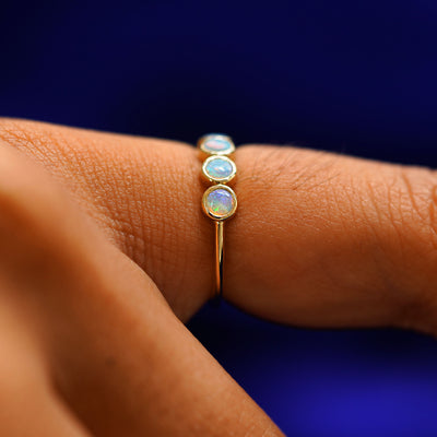Close up view of a model's finger wearing a yellow gold 5 Opals Ring to show its side