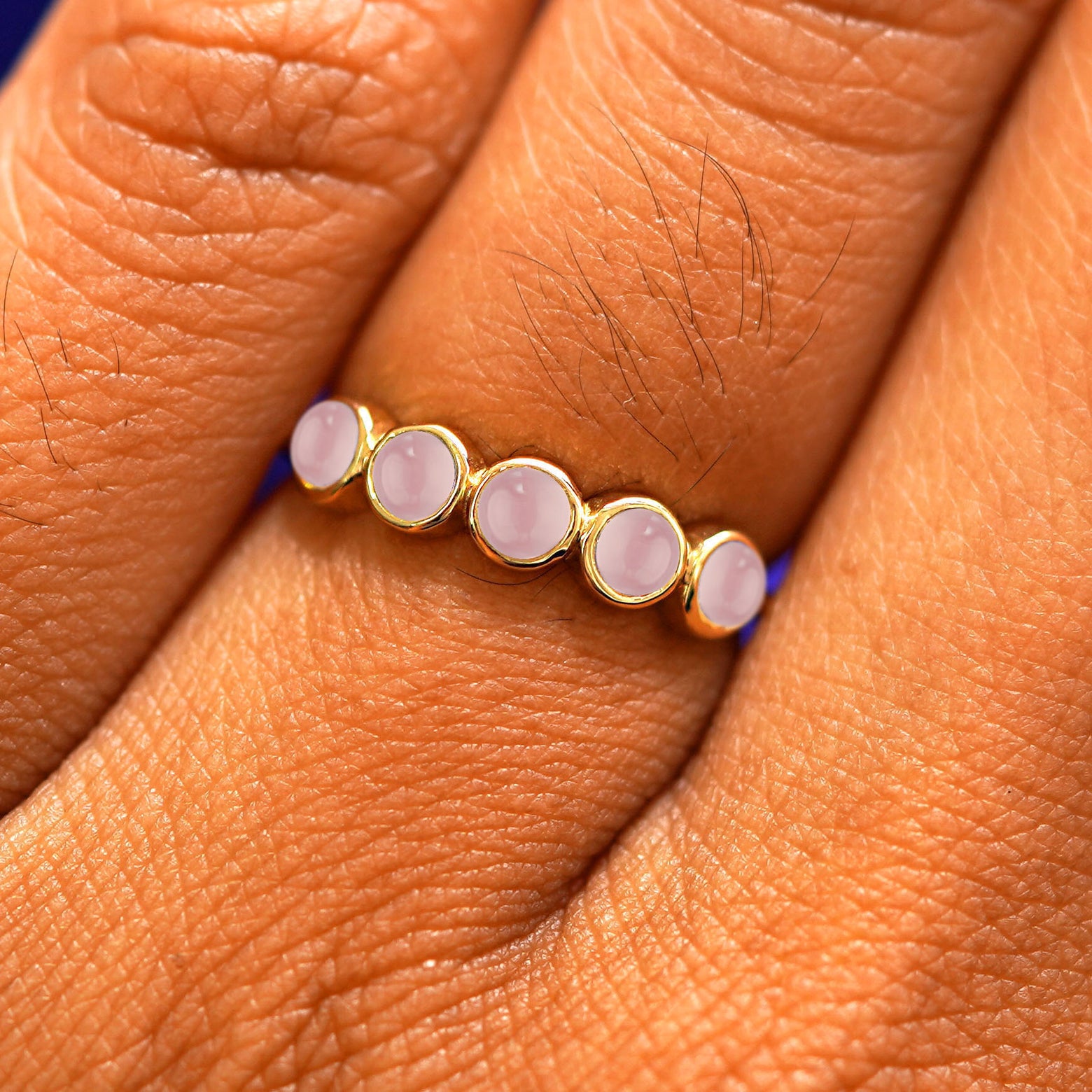 Close up view of a model's hand wearing a yellow gold 5 Gemstones Ring in rose quartz