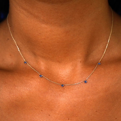 A model's neck wearing a solid 14k yellow gold 5 Gemstone Cable Necklace in sapphire