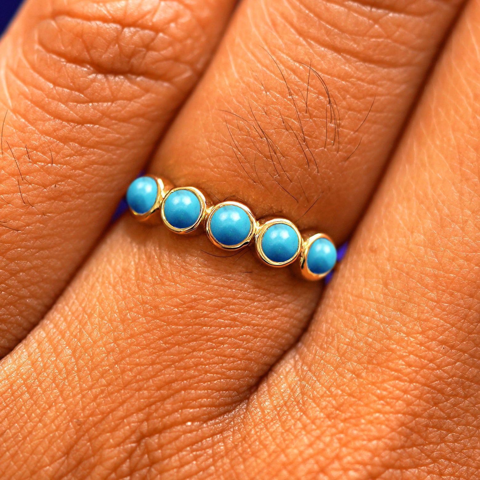 Close up view of a model's hand wearing a yellow gold 5 Gemstones Ring in turquoise
