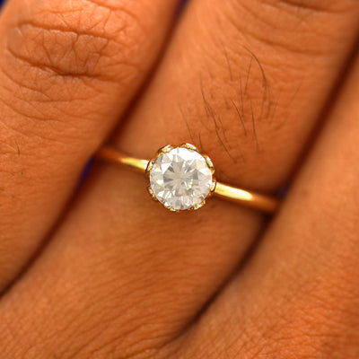 Close up view of a model's fingers wearing a 14k yellow gold Diamond Petal Ring