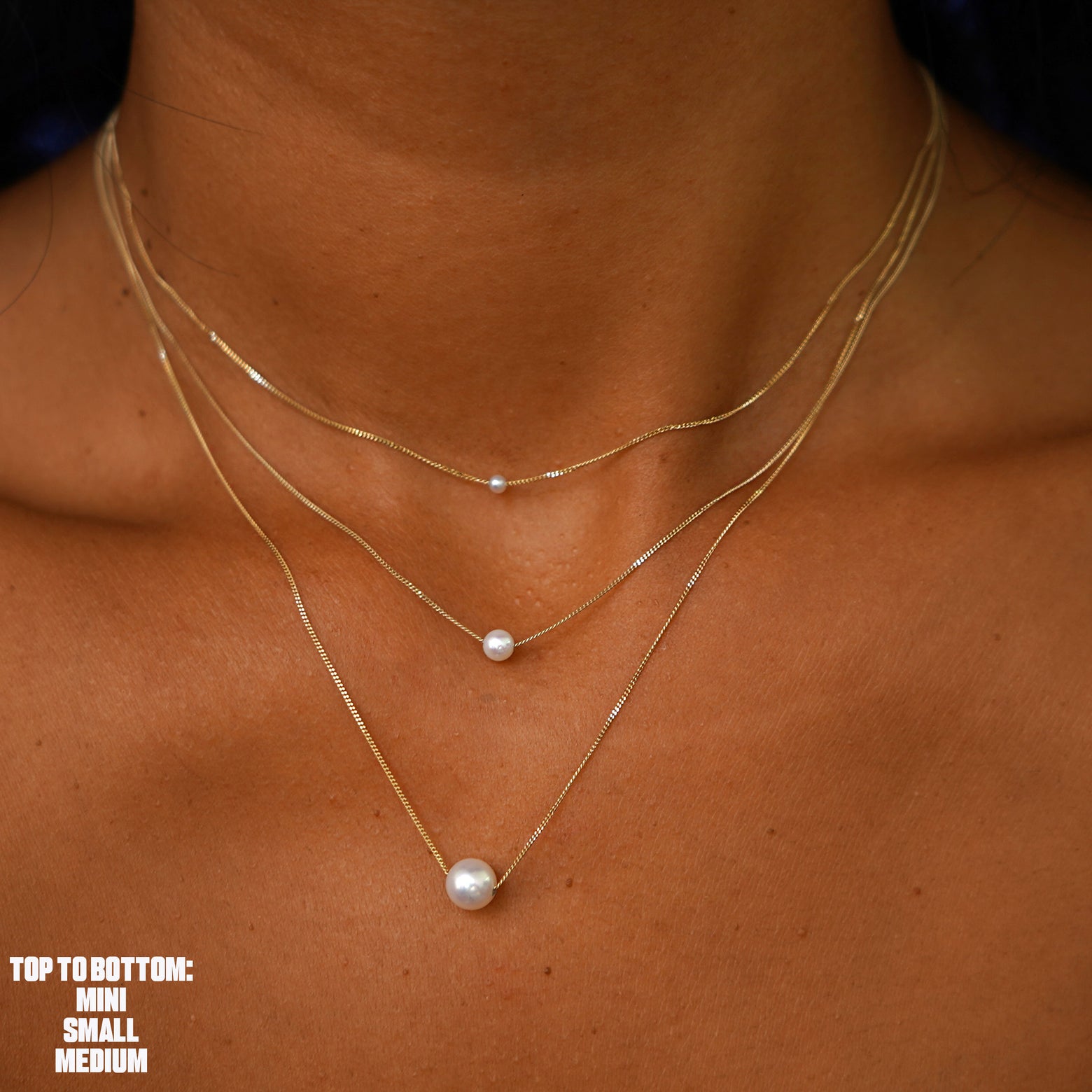 A model wearing all three sizes of the Pearl Slide Necklace layered from smallest to largest pearl
