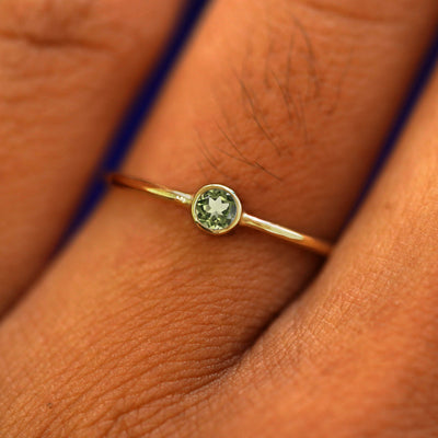 Close up view of a model's fingers wearing a 14k solid gold peridot gemstone ring