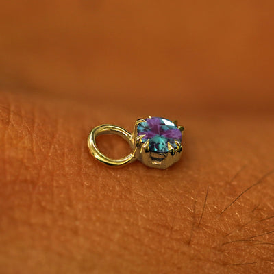 A solid yellow gold Alexandrite Charm for earring resting on the back of a model's hand