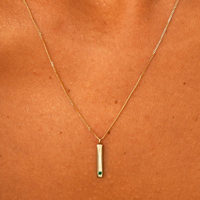 Close up view of a model's neck wearing a solid yellow gold emerald Gemstone Bar Necklace