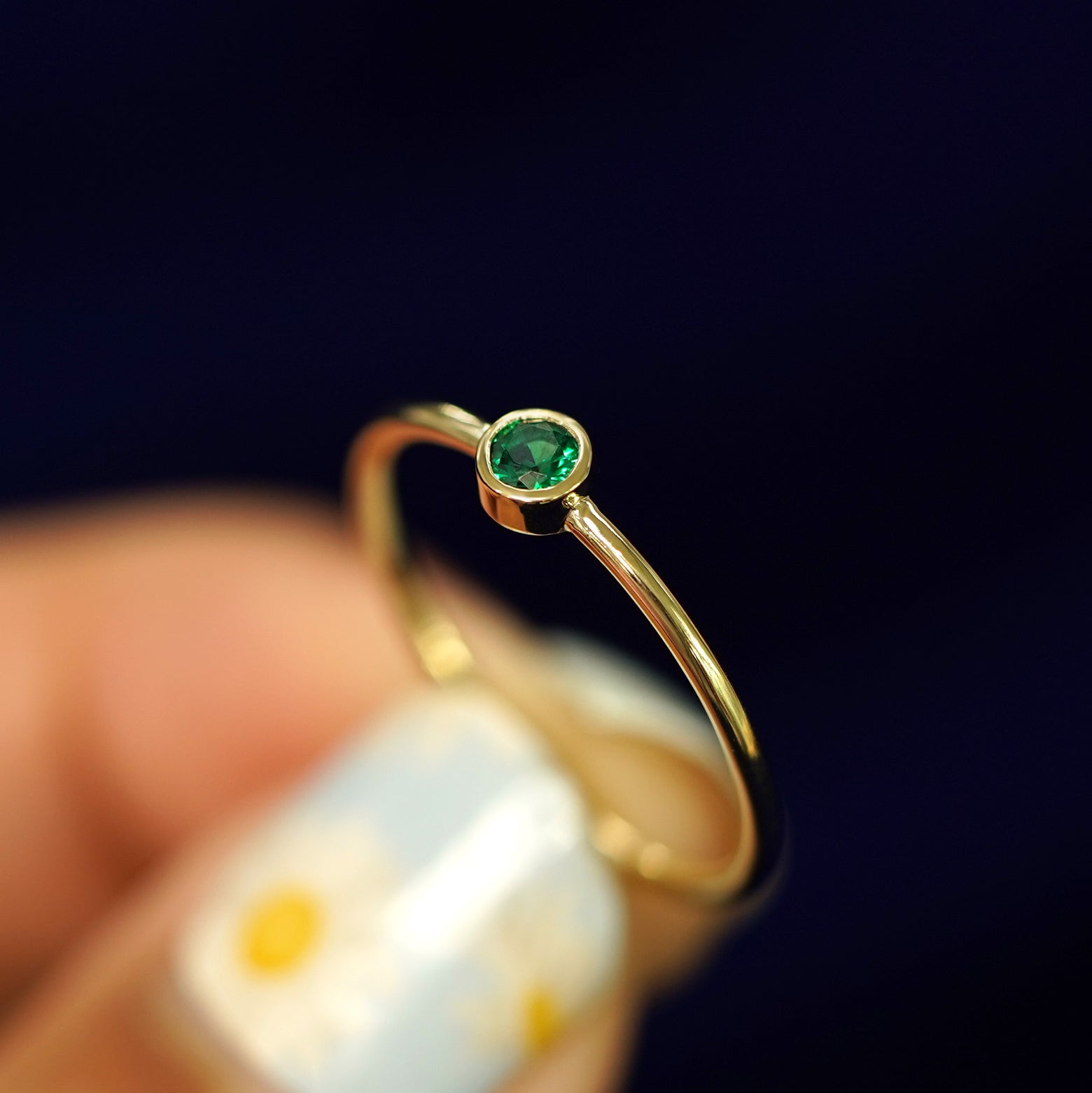 A model holding an Emerald Ring tilted to show the bezel setting