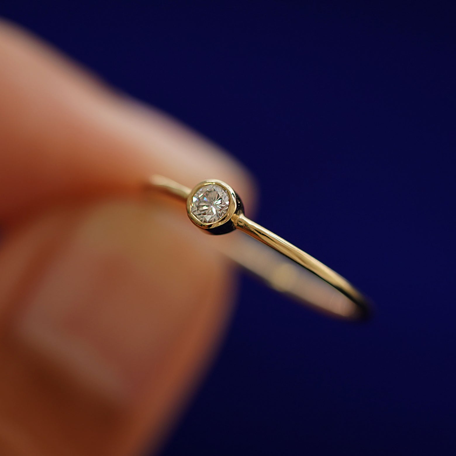 A model holding an Moissanite Ring tilted to show the bezel setting