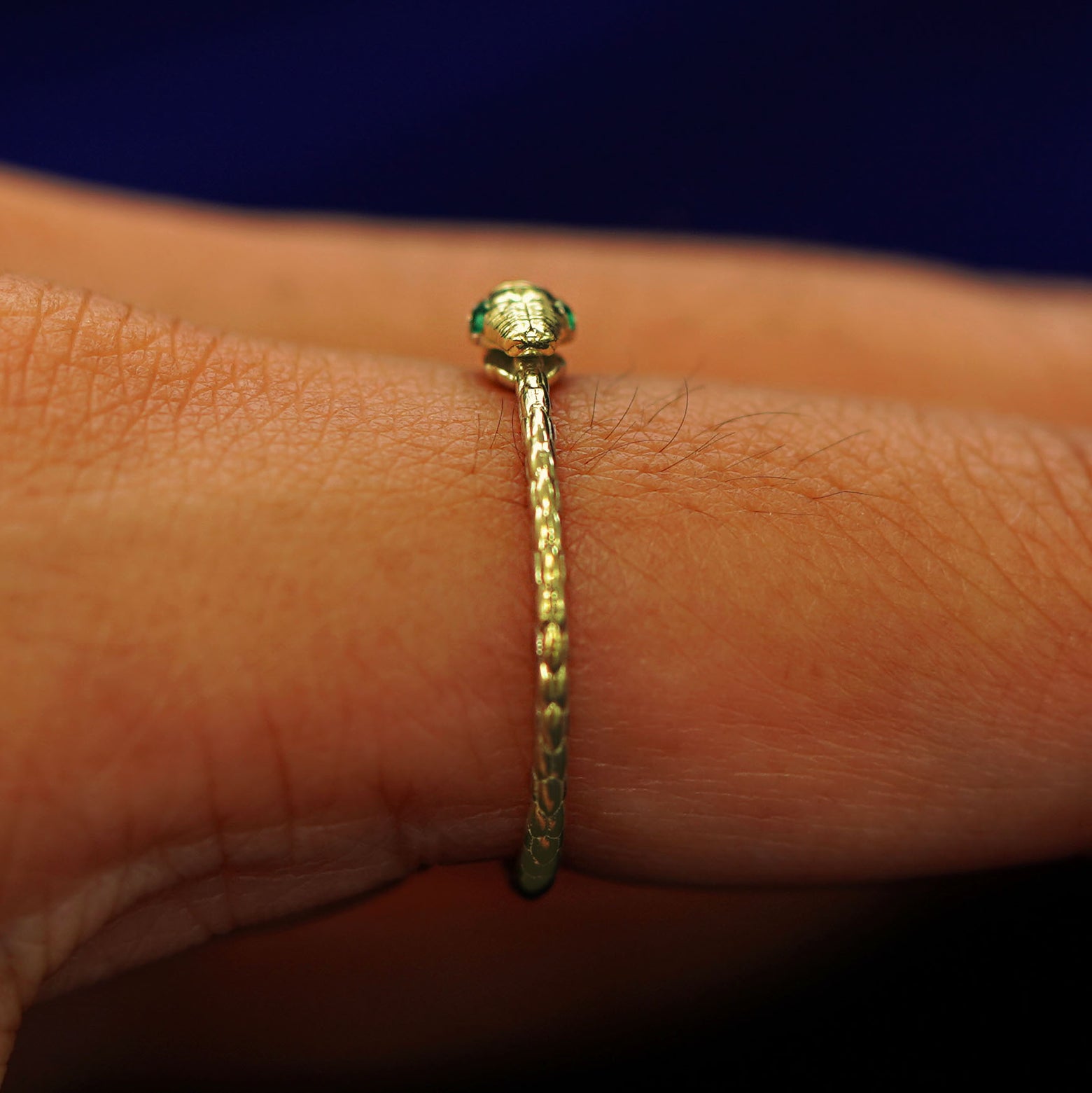 Side view of a Gemstone Ouroboros Snake Ring on a model's finger showing the snakes face