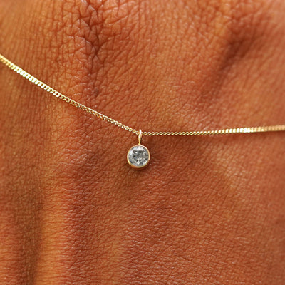 Close up view of a 14k yellow gold Salt and Pepper Diamond Necklace draped across the back of a model's hand