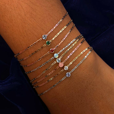 A model's wrist wearing eight different Gemstone Bracelets with different stones in different metal colors