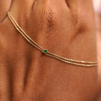 A solid gold emerald Gemstone Cable Bracelet resting on the back of a model's hand