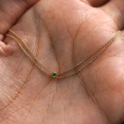 A yellow gold emerald Gemstone Cable Bracelet draped on a model's palm