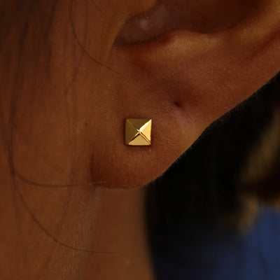 Close up view of a model's ear wearing a yellow gold Pyramid Earring