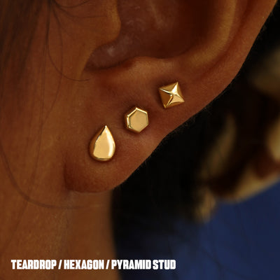 A model's ear wearing a Pyramid, Hexagon, and a Teardrop Earring in three lobe piercings