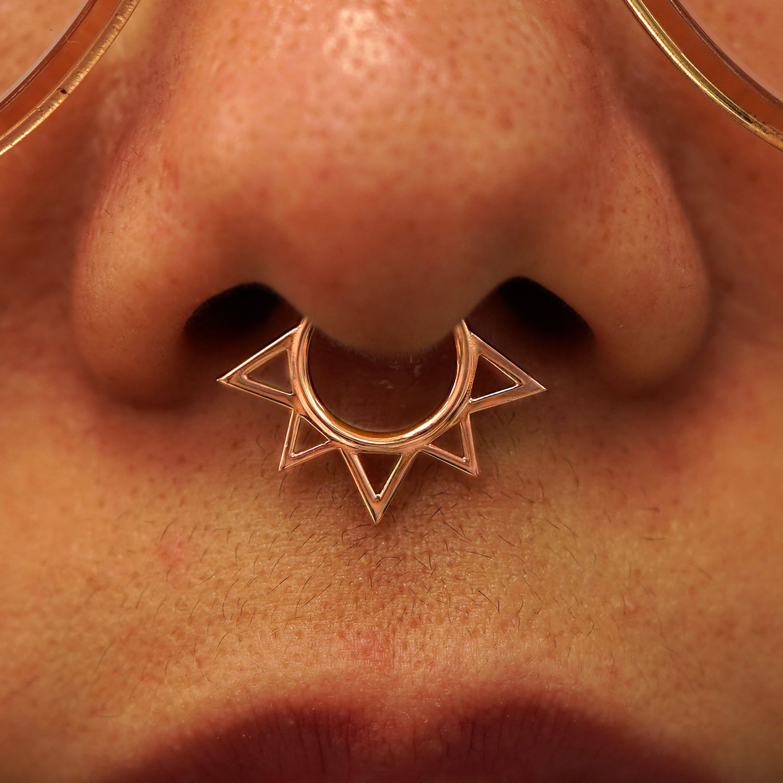 Close up view of a model's nose wearing a 14k rose gold Sun Septum