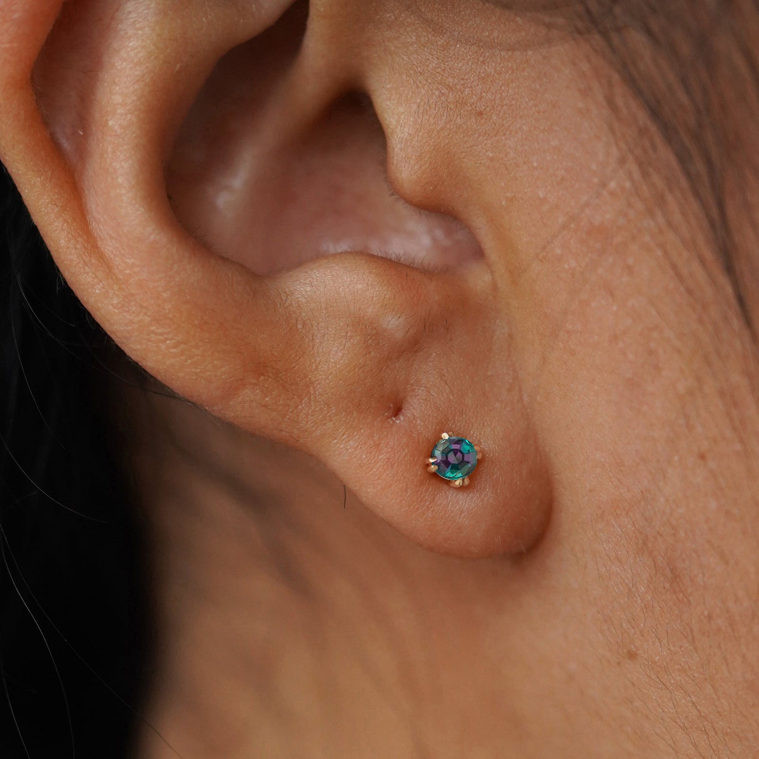 Close up view of a model's ear wearing a yellow gold Alexandrite Flat Back Earring