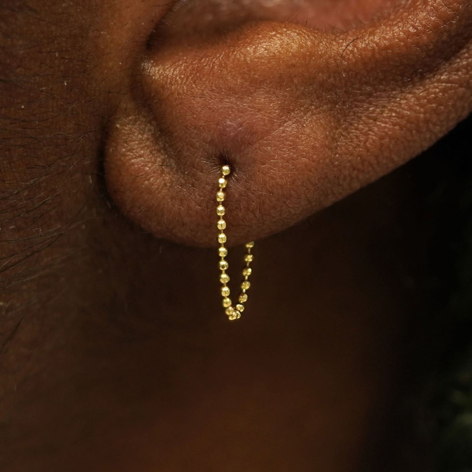 Close up view of a model's wearing a 14k yellow gold Chain Loop Earring