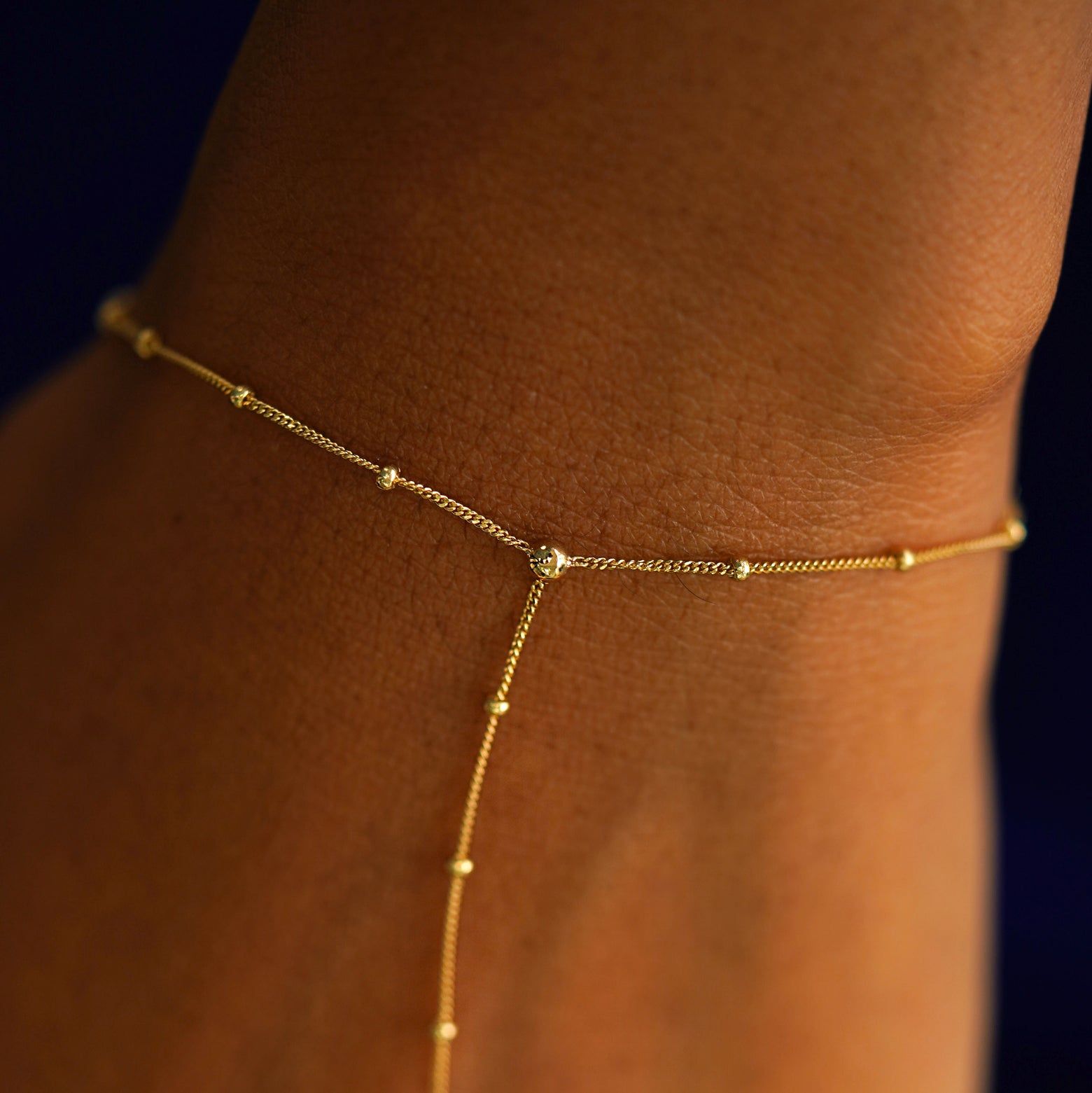 Close up view of a model's wrist wearing a 14k solid gold Beaded Essential Hand Bracelet