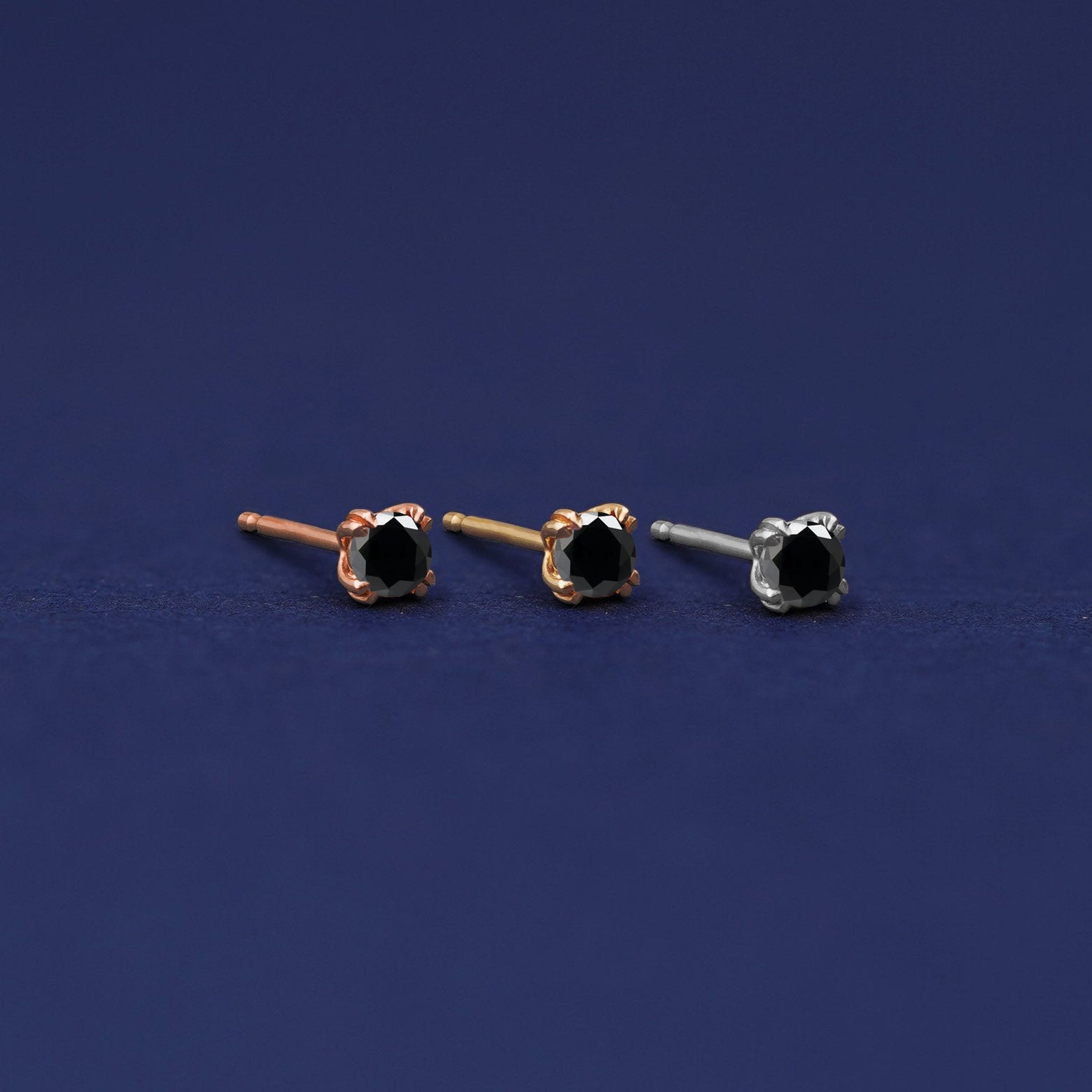 Three versions of the Black Diamond Earring shown in options of rose, yellow, and white gold