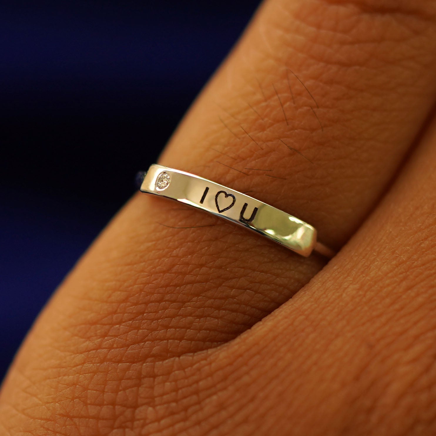 Close up view of a model's finger wearing a yellow gold diamond Gemstone Bar Ring engraved with I Heart You on the top