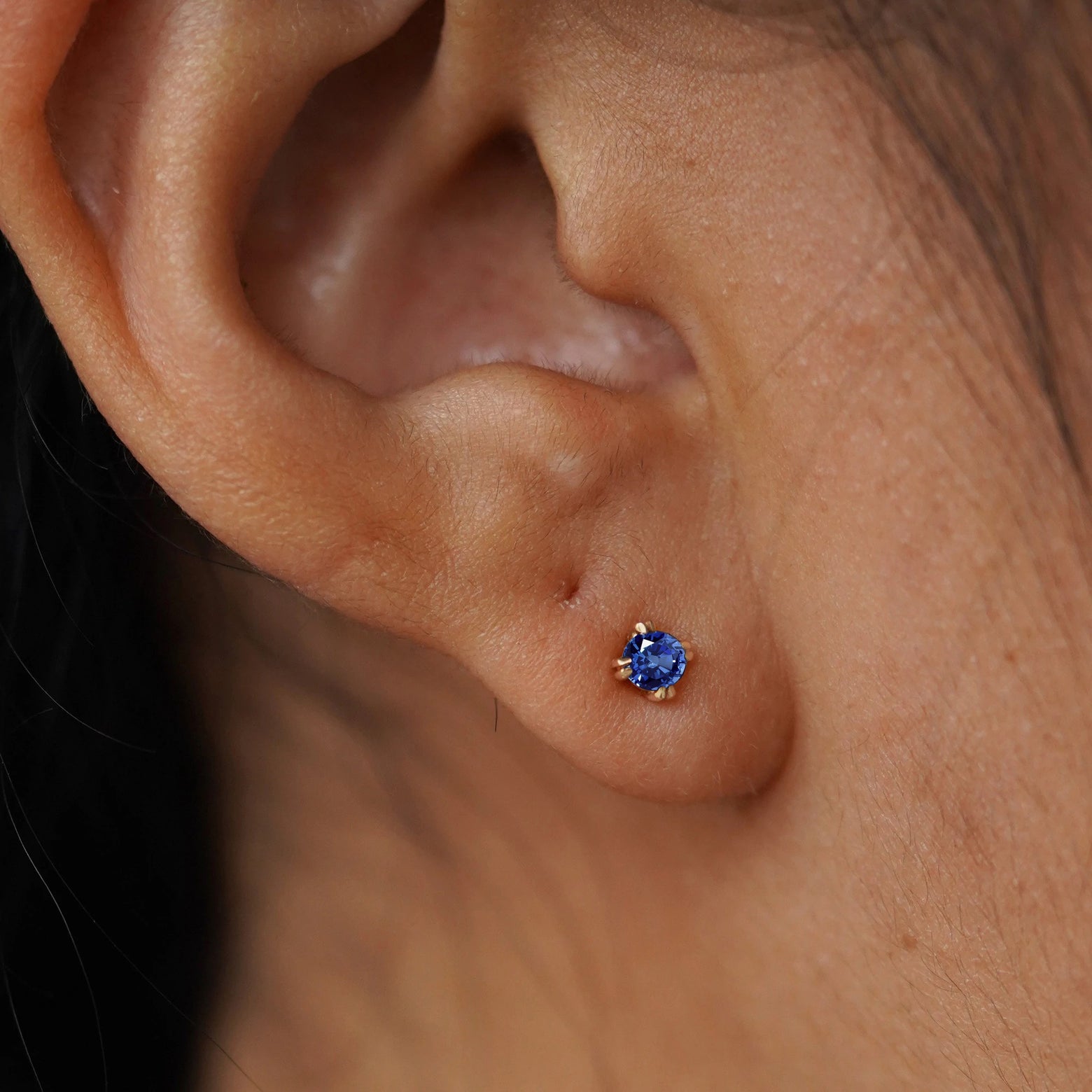 Close up view of a model's ear wearing a yellow gold Sapphire Flat Back Earring