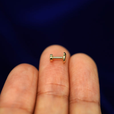 Side view of a yellow gold Screw Flatback Piercing on a model's fingertips