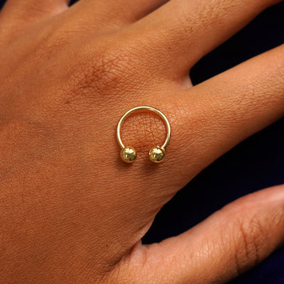 A yellow gold medium horseshoe piercing resting on the back of a model's hand to indicate size