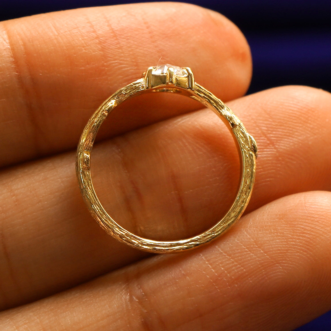 A yellow gold Moissanite Branches Ring in a model's hand showing the claw prong detailing and the whole ring
