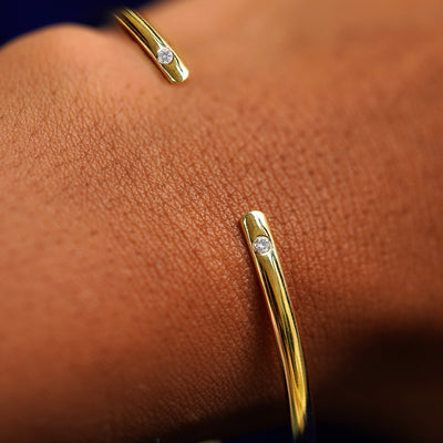Close up view of a model's wrist wearing a yellow gold Diamond Open Bangle Bracelet
