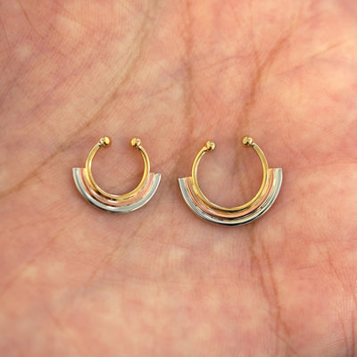 A model's palm holding two versions of the non-pierced Rainbow Septum showing the 8mm and 10mm sizes