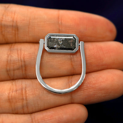 A white gold Salt and Pepper Diamond Spinner Ring in a model's hand with the diamond spun the other way