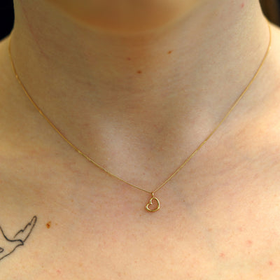 A model's neck wearing a 14k yellow gold Heart Necklace