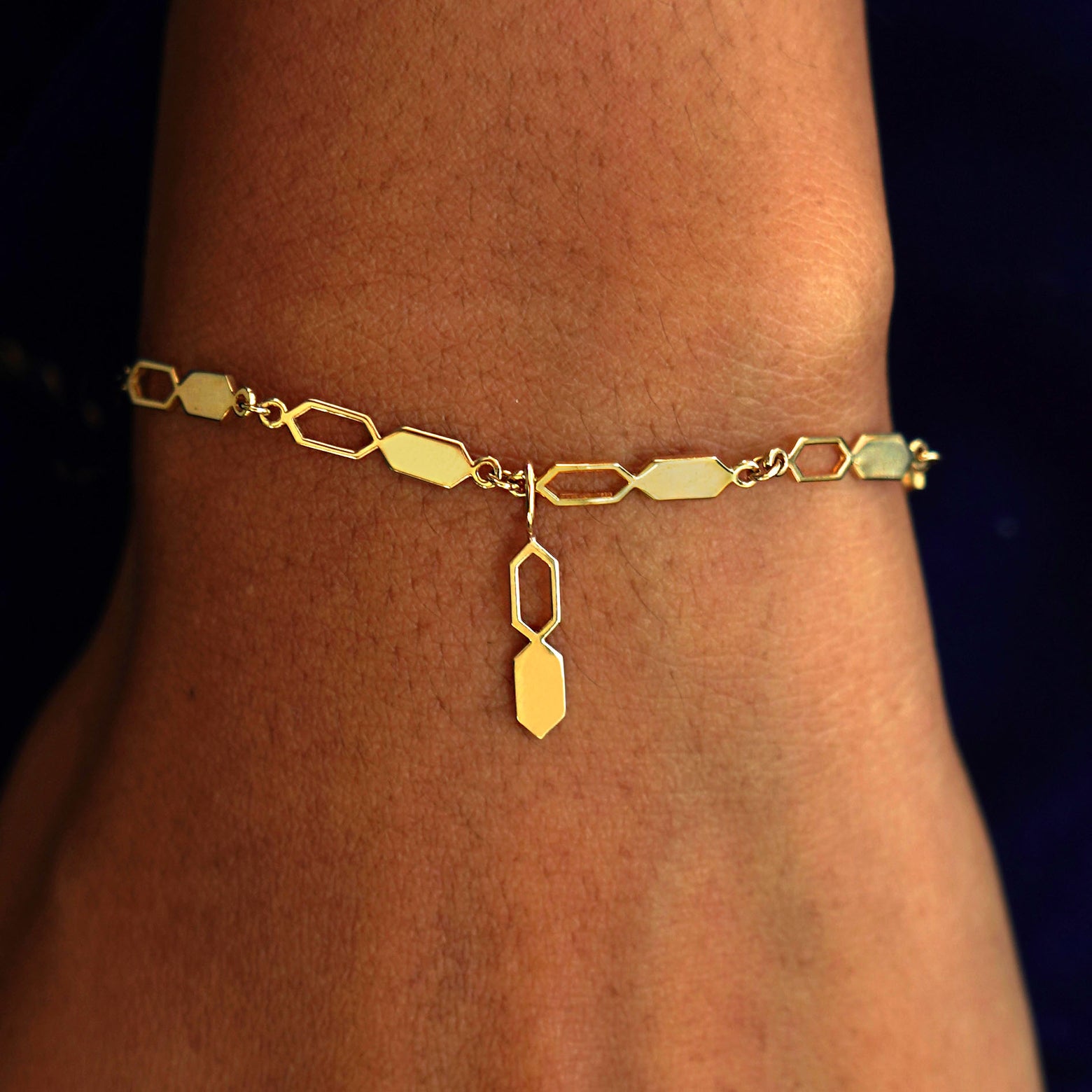 A model's wrist wearing a yellow gold Tanlah Chain with a Tanlah Charm