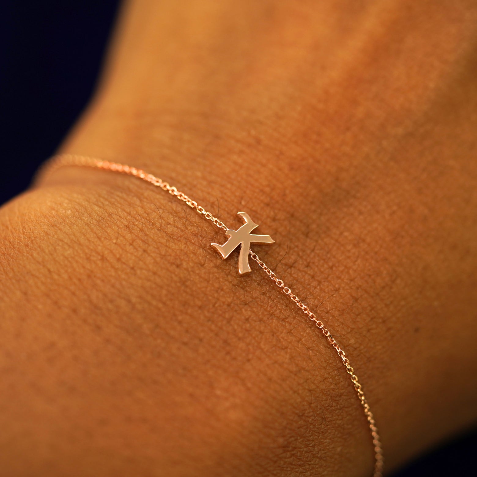 A model's wrist wearing a 14k solid rose gold Initial Bracelet in the letter K