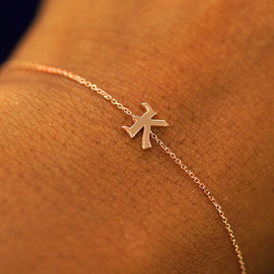 Close up view of a model's wrist wearing a 14k solid rose gold Initial Bracelet in the letter K