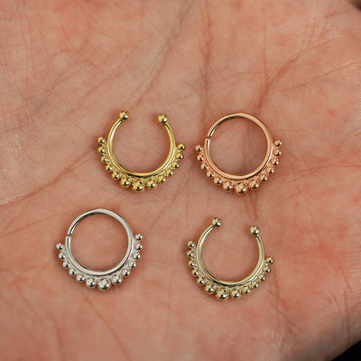 Four versions of the Beaded Septum shown in options of yellow, white, rose and champagne gold in a model's palm