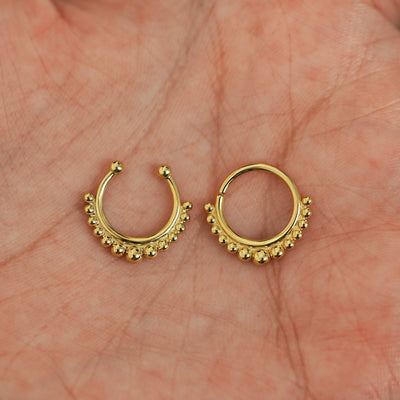 Two 14k solid gold Beaded Septum rings show in options of Non-Pierced and Pierced resting in the palm of a model's hand