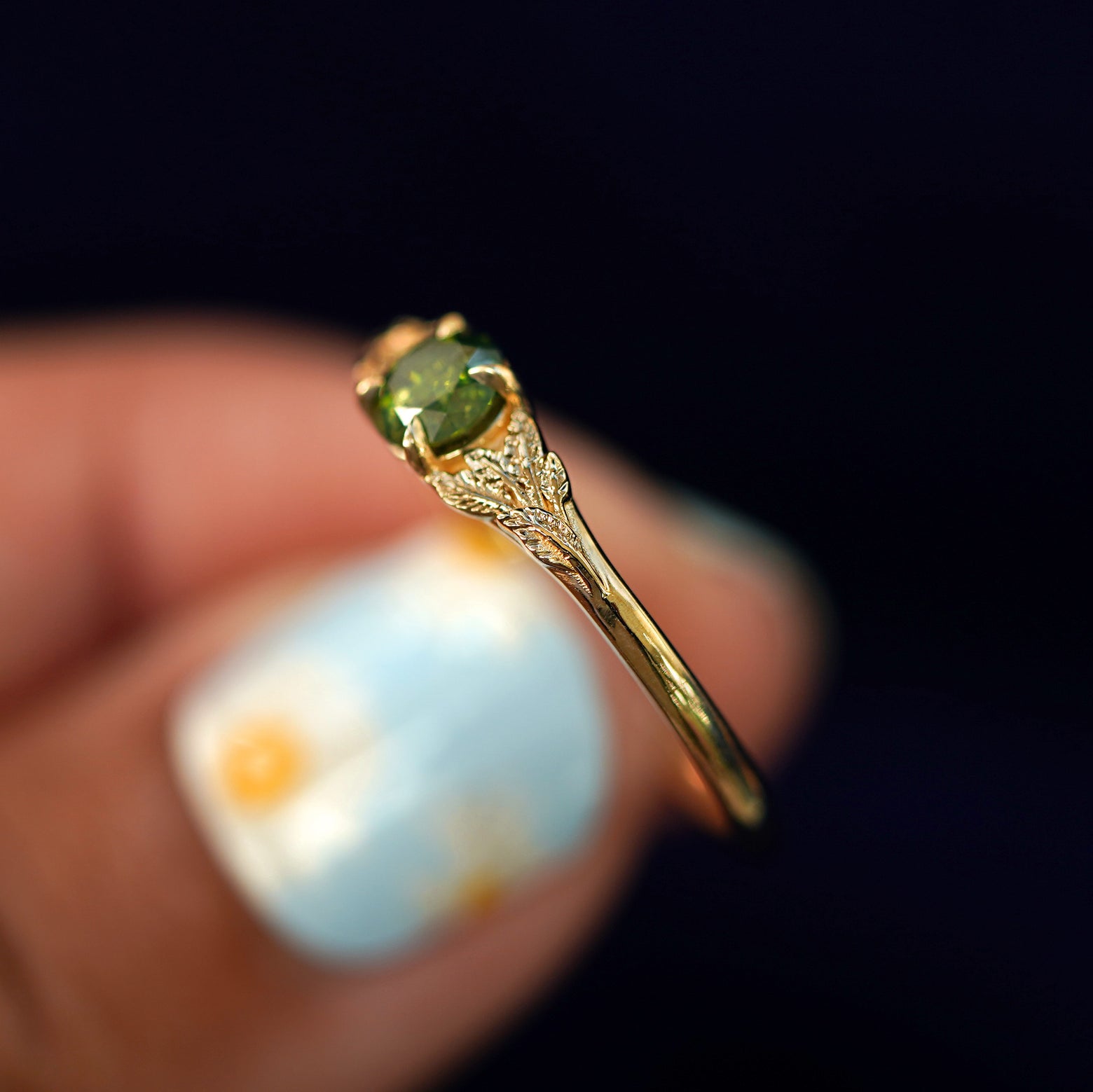 A model holding a Green Diamond Leaves Ring tilted to show the side of the ring