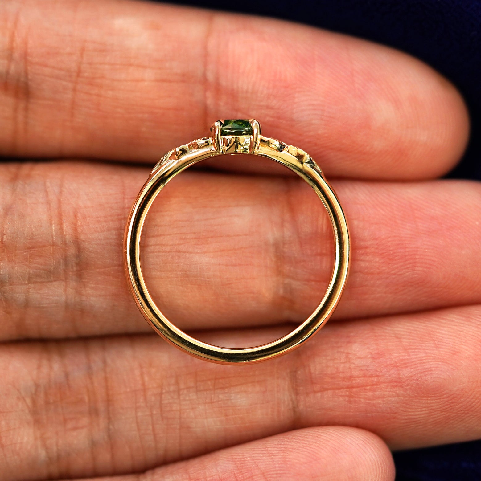 A yellow gold Green Diamond Leaves Ring in a model's hand showing the thickness of the band