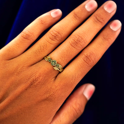 Close up view of a model's hand wearing a yellow gold Green Sapphire Leaves and Vines Ring