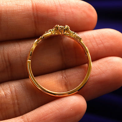 A yellow gold Green Sapphire Leaves and Vines Ring in a model's hand showing the thickness of the band